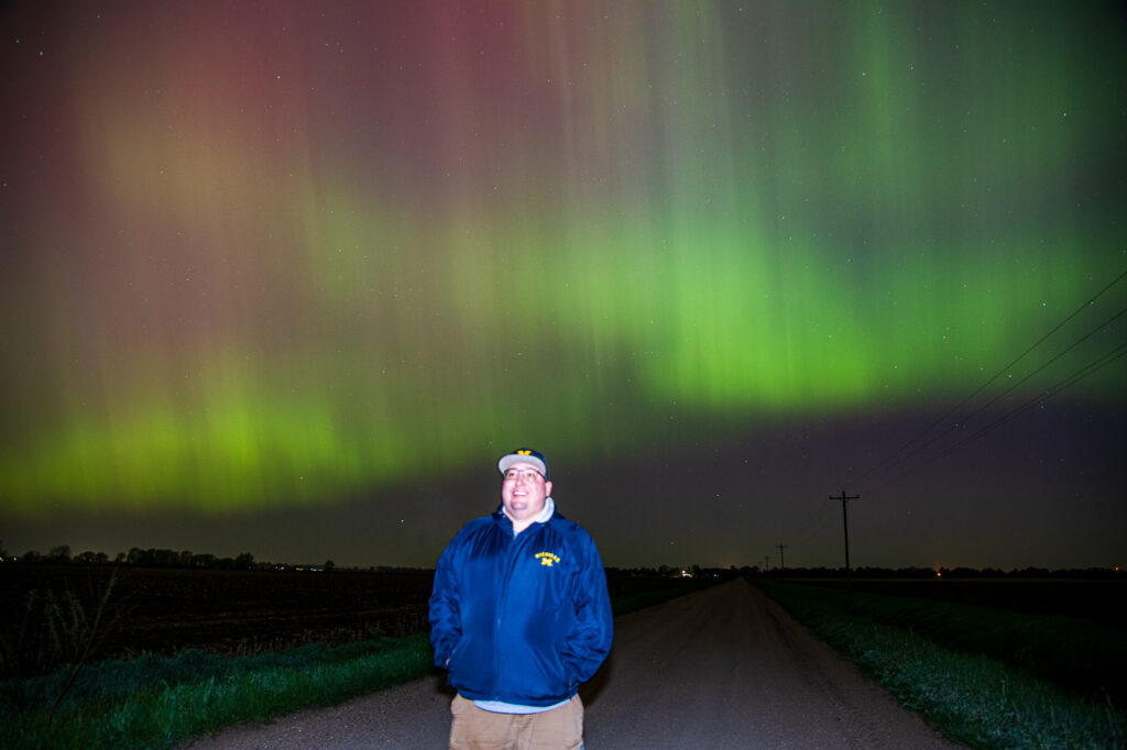 Ben Holcomb standing under auroras in Nebraska